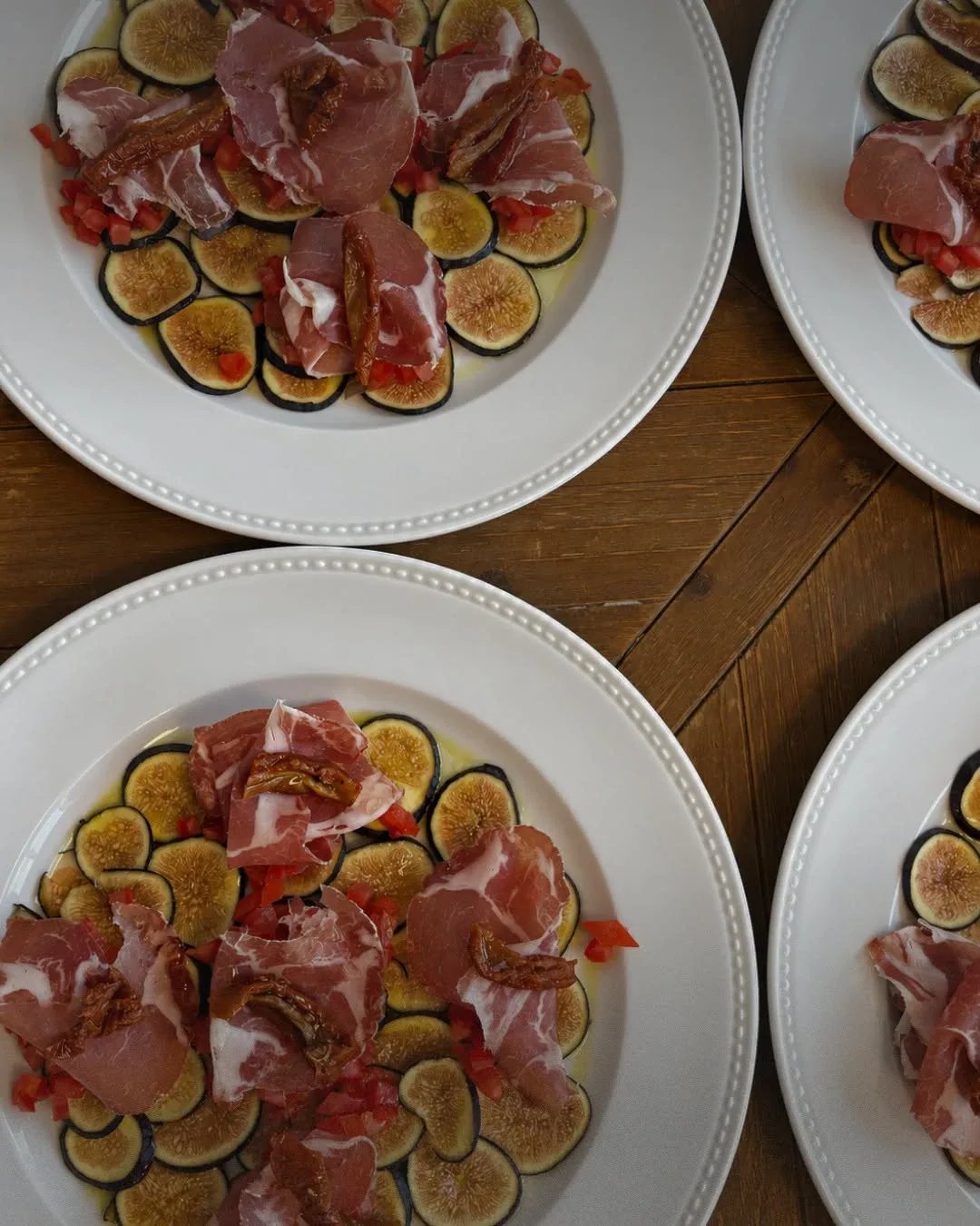 Pratos de figos laminados com presunto, tomate seco e azeite, vistos de cima