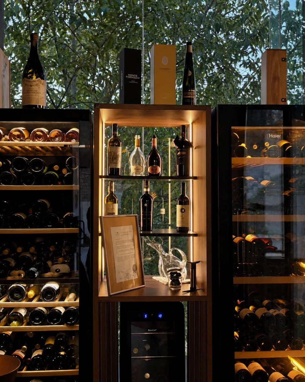 Garrafeira iluminada do Basilic, com vinhos expostos frente à janela e às árvores