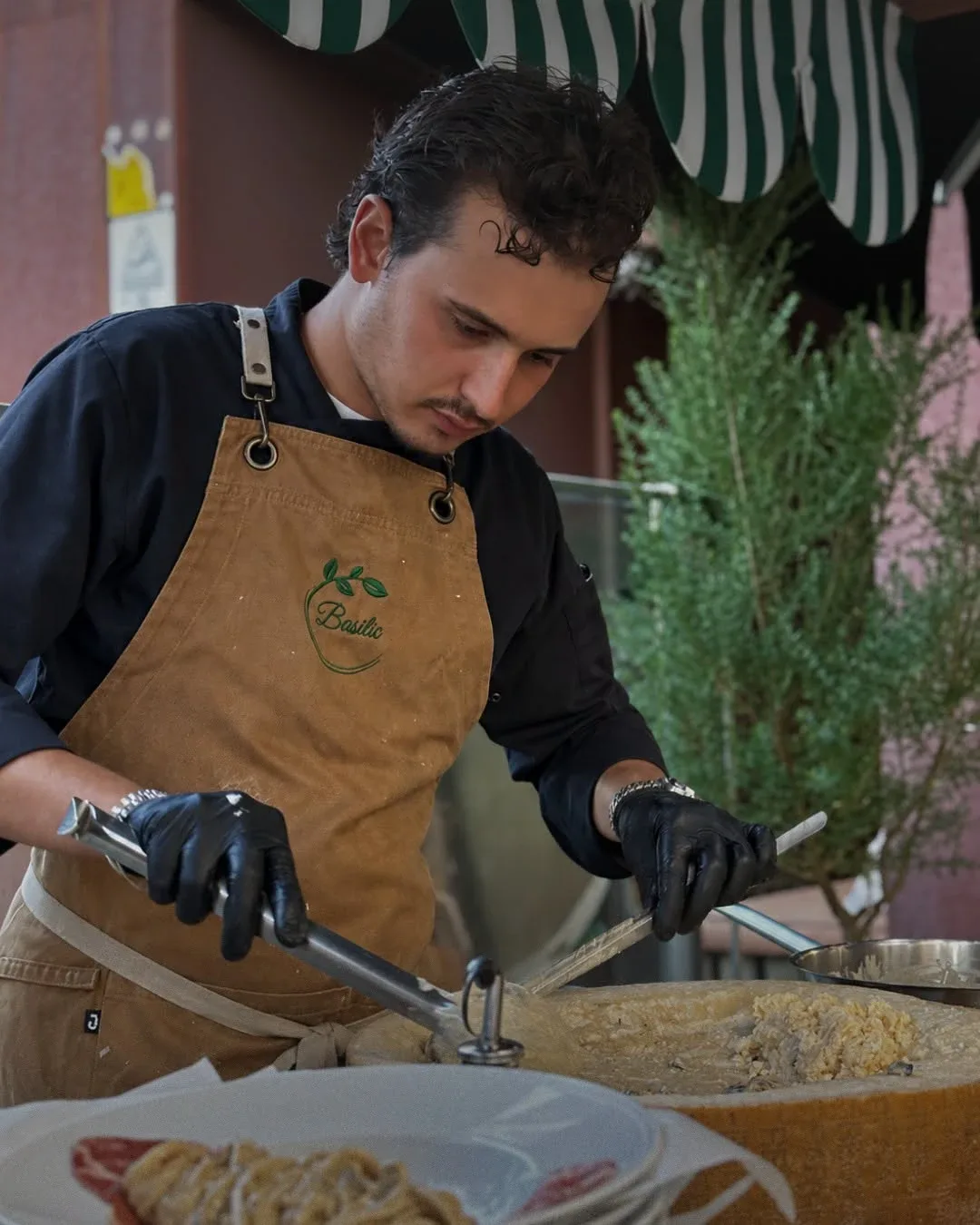 Cozinheiro do Basilic a envolver massa numa forma de queijo parmesão