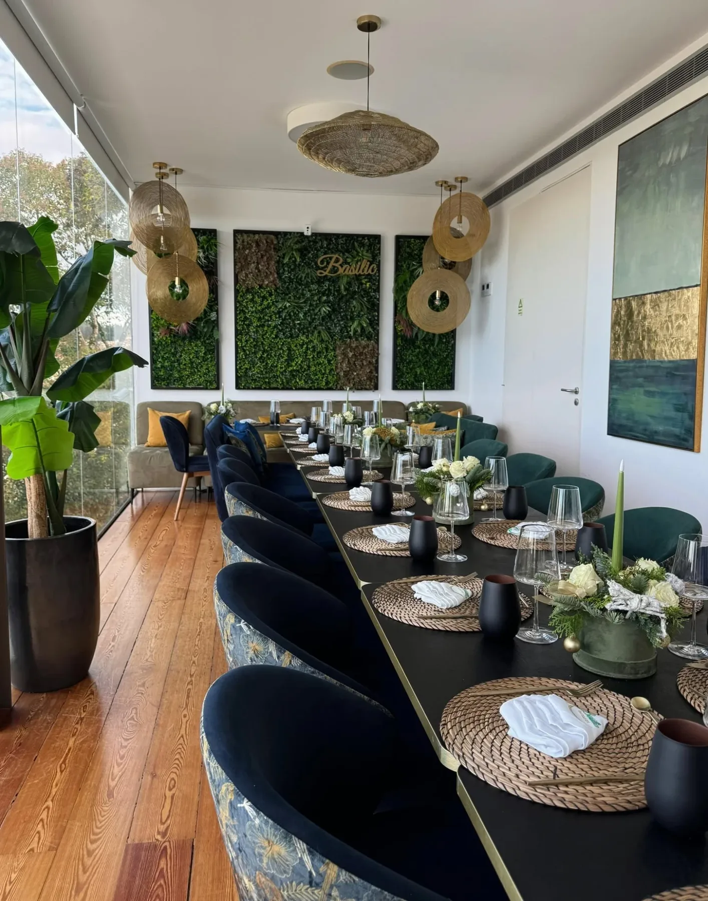 Sala do Basilic com parede verde, candeeiros dourados e mesa posta